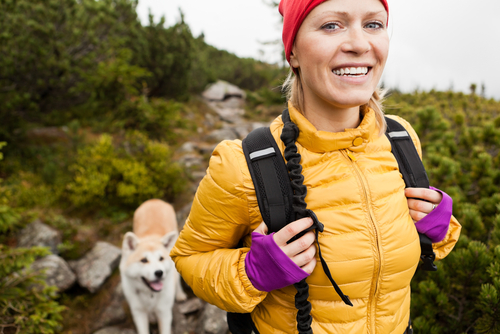 Happy smiling woman hiking in mountains with akita dog