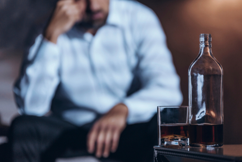 Whiskey bottle and glass with a depressed manq