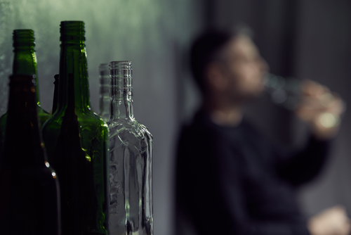 Empty bottles of alcohol with drinking man