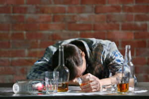 Drunk man at table with alcohol and drugs