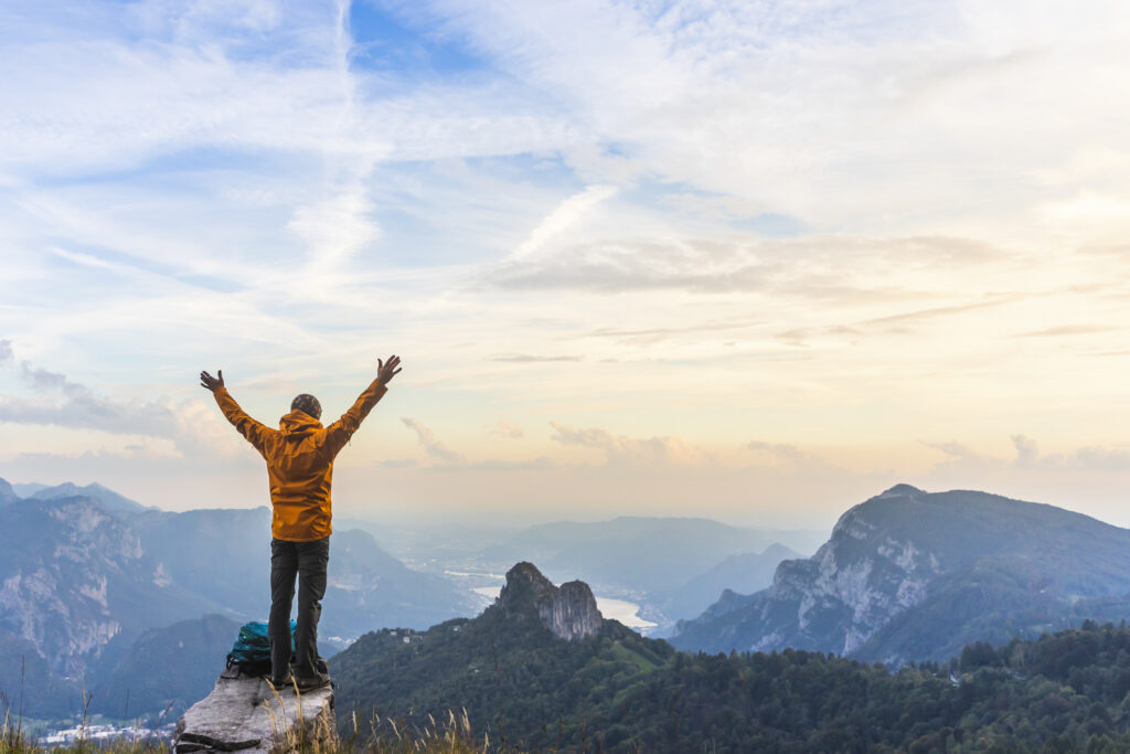 man on mountain top at sunset finding happiness in recovery