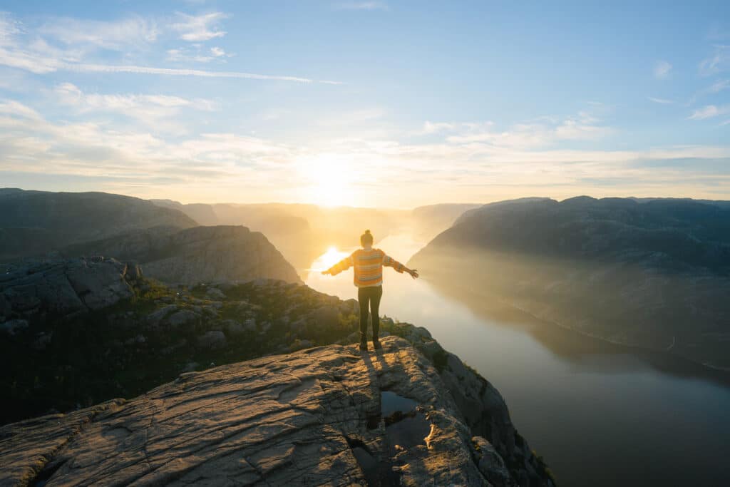 A person stands on a mountain trail at sunrise, symbolizing self-reflection and the journey toward hope and healing.