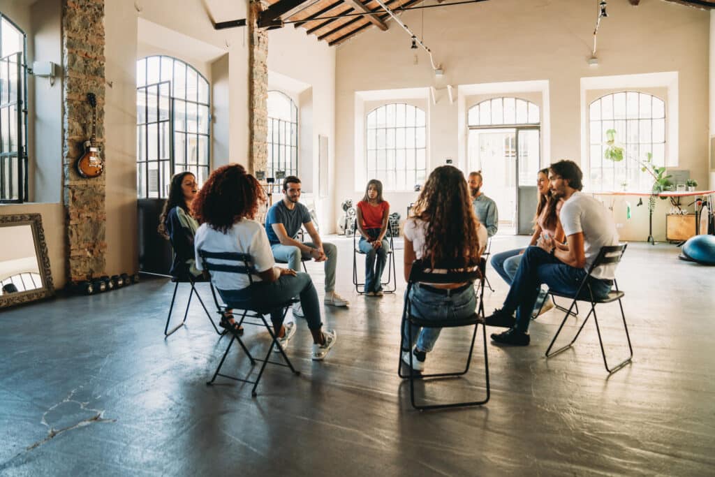 roup of individuals seated in a circle during a 12-step meeting, sharing experiences and offering support in early recovery.