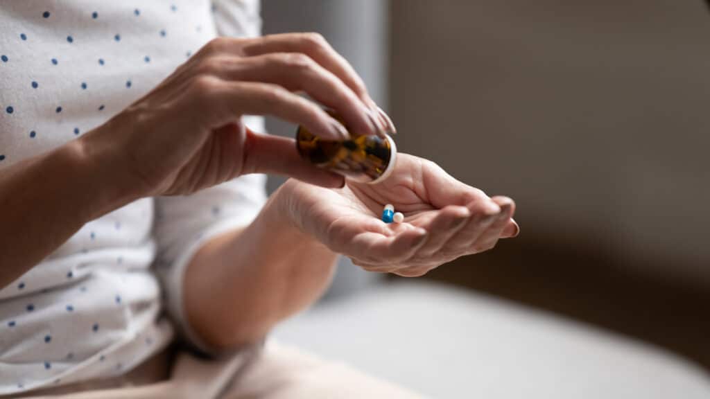 Close up of woman’s hands holding prescription medication due to addiction