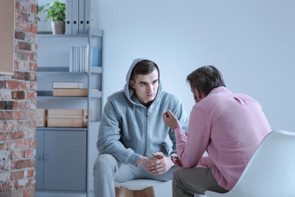 Two men talking with serious expressions due to addiction relapse