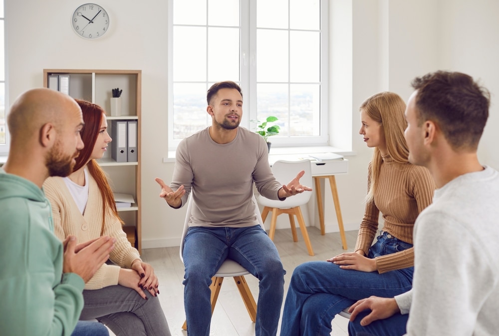 A man speaking in a group therapy circle during a partial hospitalization program