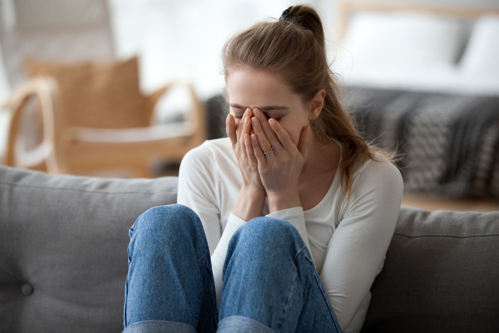 A woman struggling with substance use and body image covering her face with her hands