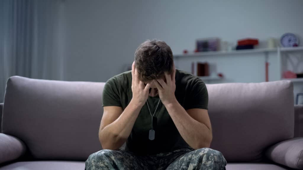 A veteran struggling with addiction sitting with his head in his hands