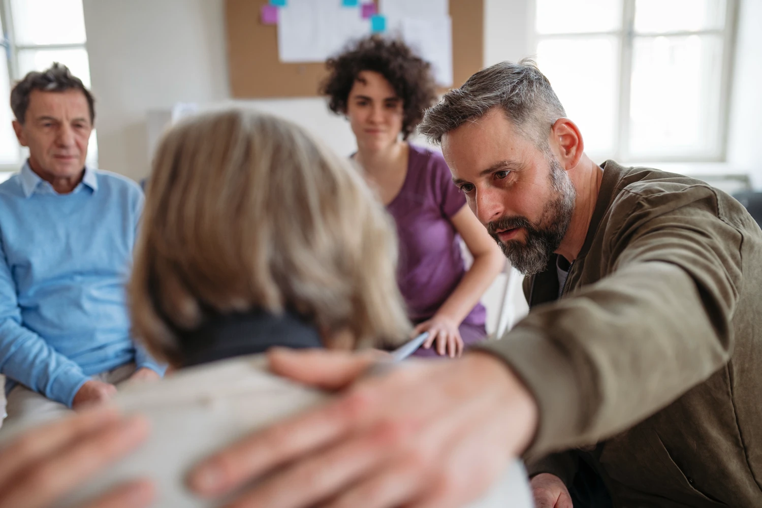 A supportive group member helping someone through addiction recovery