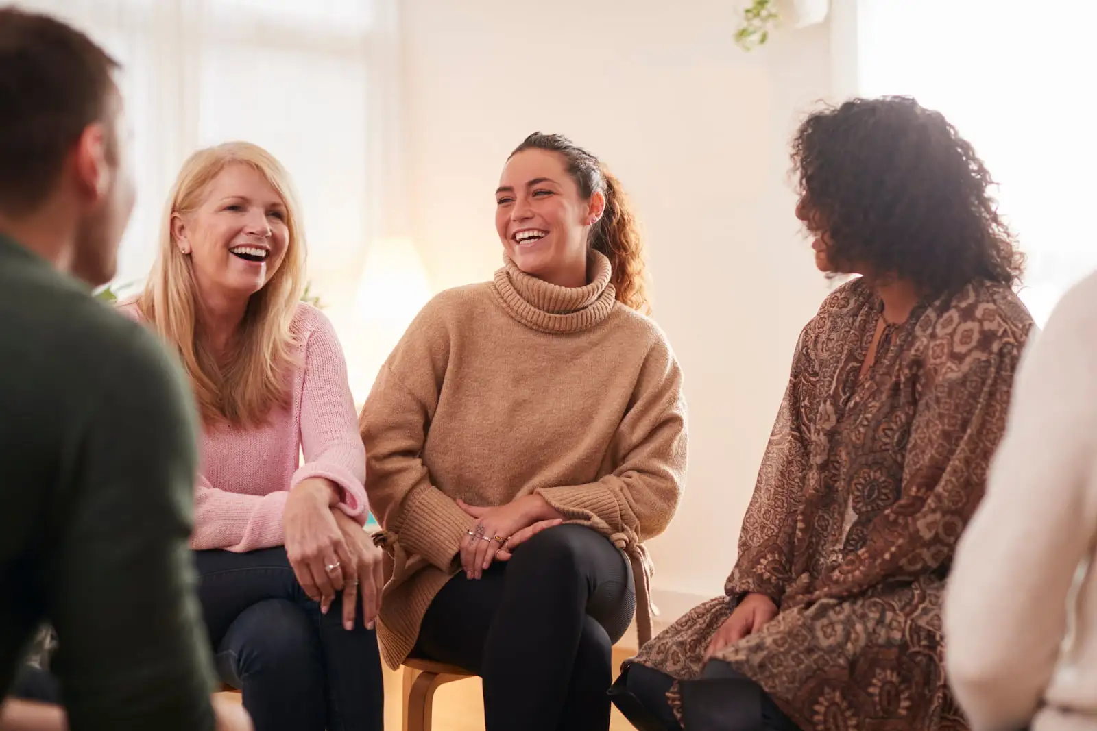 Men and women sitting together in group therapy and smiling while talking